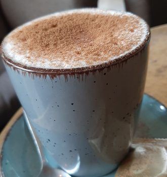 Tasse mit Tee und aufgeschäumter Milch