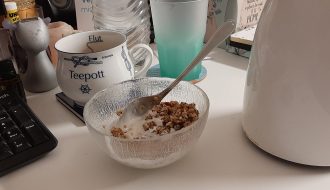 Müsli, Tasse und Teekanne auf einem Schreibtisch