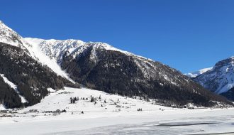 schneebedeckte Berge im Vordergrund ein gefrorener See